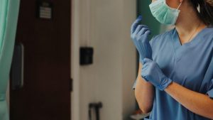 nurse wearing gloves and a mask working