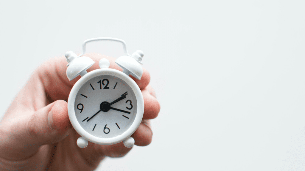 a person holding a small alarm clock