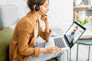 woman on her laptop sitting on couch wearing a headset